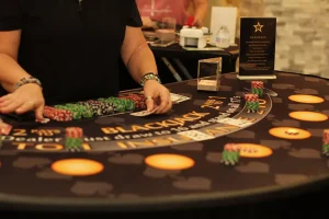 A blackjack dealer manages chips and cards at a Casino Night table, with betting areas and game instructions clearly visible on the felt.