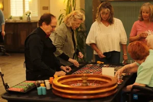 People playing roulette at a table with a dealer.