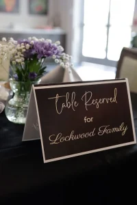 A sign with the text "Table Reserved for Lockwood Family" sits on a table decorated with vases of flowers, setting the scene for an elevated dining experience.