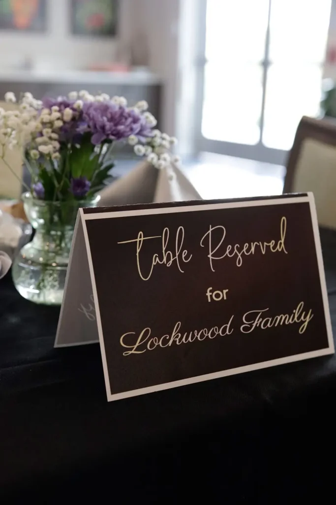 A sign with the text "Table Reserved for Lockwood Family" sits on a table decorated with vases of flowers, setting the scene for an elevated dining experience.