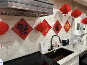A kitchen decorated with red Chinese lanterns and red diamond-shaped paper decorations with gold Chinese characters on the wall above the sink, celebrating the Lunar New Year.