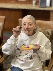 An elderly woman celebrates World Health Day as she sits in a chair, holding a blackberry and a plate of fruit.