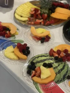 Clear plastic plates with assorted sliced fruit—cantaloupe, pineapple, strawberries, blackberries, and raspberries—arranged on a table to promote health awareness and celebrate World Health Day.